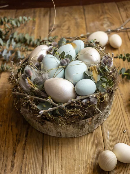 Easter nest with green eggs and willow trees on a wooden background