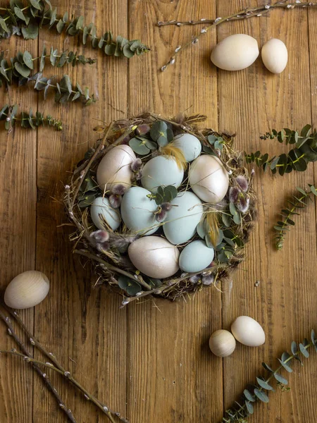 Easter nest with green eggs and willow trees on a wooden background