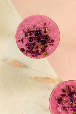 Smoothie berry smoothie pembe bir arka plan masanın üzerinde duruyor.