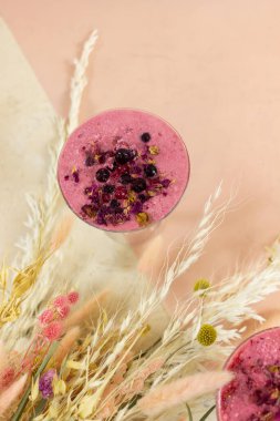 Smoothie berry smoothie pembe bir arka plan masanın üzerinde duruyor.