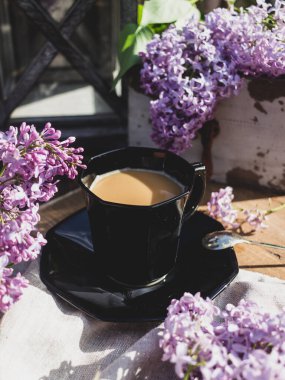Ahşap arka planda, leylak dallı bir kahve fincanı.