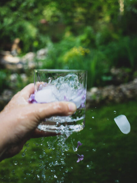 стакан льда с водой и цветами сирени