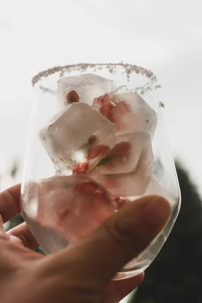 A glass with ice cubes and a pink drink