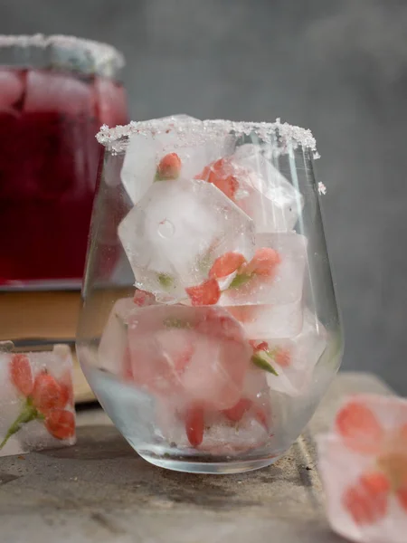 A glass with ice cubes and a pink drink