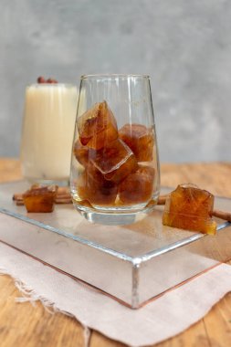 Sütlü ve buzlu yaz içeceği. Ahşap arka planda bir bardakta buz.