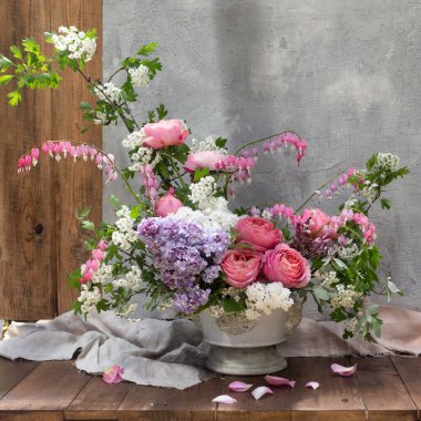 Yaz çiçekleriyle, güllerle, leylaklarla dolu gri bir arka planda vazoda