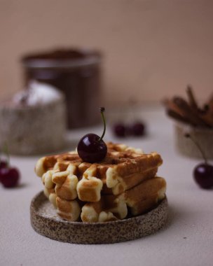 Kremalı ve kirazlı seramik tabakta waffle ile tatlı.