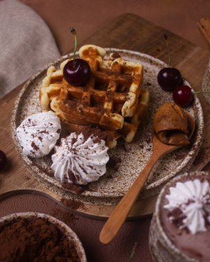 Kremalı ve kirazlı seramik tabakta waffle ile tatlı.