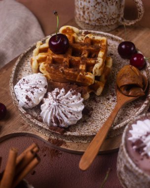 Kremalı ve kirazlı seramik tabakta waffle ile tatlı.