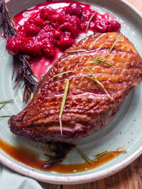 Mavi tabakta kiraz soslu kızarmış ördek.