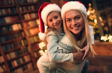Güzel bir anne ve kızı var, Noel şapkaları var, Noel ağacı ışıkları var. Portre tatili. Kış dönemi. Aile çocukları portresi. Yeni yıl dekorasyonu.