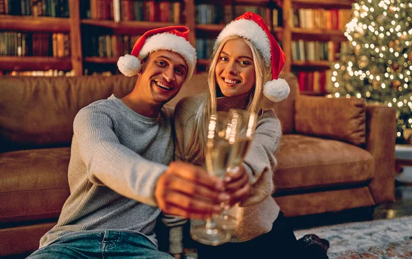 Krásný Mladý Pár Santa Klobouky Drží Sklenice Šampaňského Usmívá Při — Stock fotografie