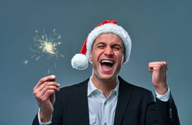 Attractive man with sparklers celebrates New Year. Studio shooting on a gray background.