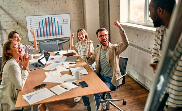 Heyecanlı Afrikalı ve Kafkasyalı iş adamları zafer, başarı ya da iyi performansla motive edilirken, çok uluslu bir grup çalışan birlikte kurumsal başarıyı kutluyor..