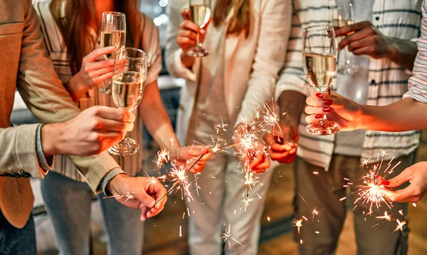 Mutlu noeller ve mutlu yıllar! Çok ırklı genç yaratıcı insanlar bayramı modern bir ofiste maytaplarla kutluyor. Bir grup genç iş adamı iş yerinde şampanya içiyor..