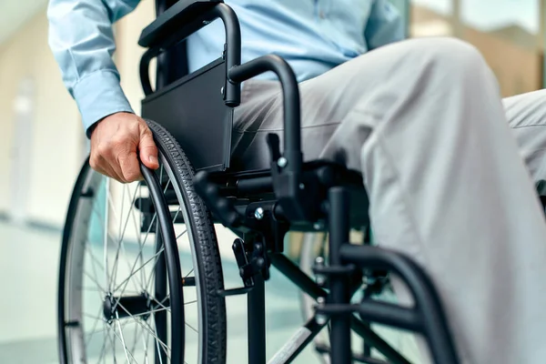 Close-up of disabled elderly man sitting in wheelchair being cared for in hospital, disabled mature grandfather in wheelchair, elderly disability concept.