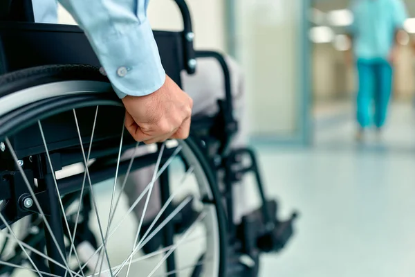 Close-up of disabled elderly man sitting in wheelchair being cared for in hospital, disabled mature grandfather in wheelchair, elderly disability concept.