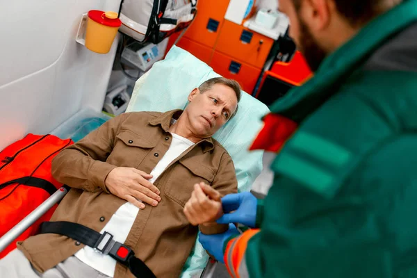 Paramédico Uniforme Mede Pulso Paciente Sênior Deitado Uma Maca Uma — Fotografia de Stock