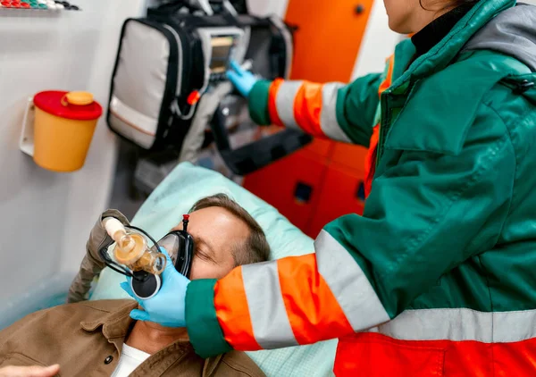 Sanitariuszka Mundurze Zakłada Respirator Tlenem Pomóc Starszemu Pacjentowi Leżącemu Pulsoksymetrem — Zdjęcie stockowe