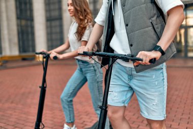 Çekici bir kız ve elektrikli scooterlı çekici bir adam. Kampüsün yakınında scooter kullanan birkaç öğrenci..