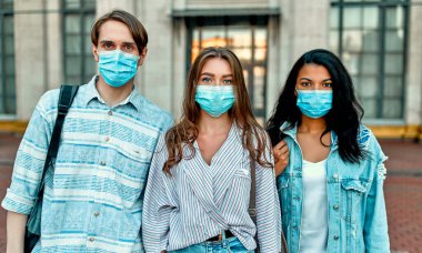 Kampüsün yakınlarında koruyucu tıbbi maskeler takan bir grup öğrenci..