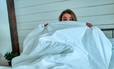 Yatakta güzel bir genç kadın var. Gözleri açık genç kız sabahları yüzünü beyaz battaniyeyle örtüyor. Uyku konsepti yeterli değil..