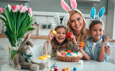 Mutlu Paskalyalar! Anne, oğul ve kız Paskalya yumurtaları için avlanmaya başlar. Mutlu aile Paskalya için hazırlanıyor. Paskalya günü tavşan kulağı takan şirin bir kız ve erkek..