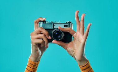 Profesyonel kamera önünde fotoğraf çeken kadın elleri mavi arka planda izole edilmiş..