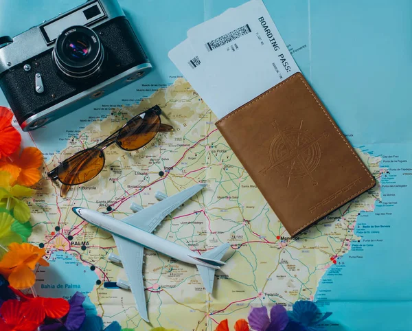 Embark on an adventure. Map, plane, camera, glasses and passport with tickets on the table. Travel, vacation concept. Top view.