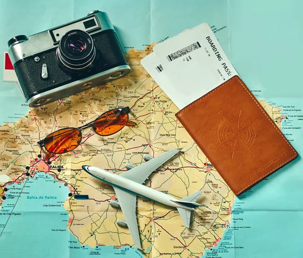 Embark on an adventure. Map, plane, camera, glasses and passport with tickets on the table. Travel, vacation concept. Top view.