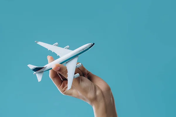 Toy airplane model in hand isolated on a blue background. Security concept.