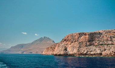 Mavi denizin çarpıcı deniz manzarası uçurumların arka planına ve bulutsuz gökyüzüne karşı.