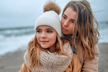 Güzel, genç bir anne ve güzel kızı kışın kumsalda..