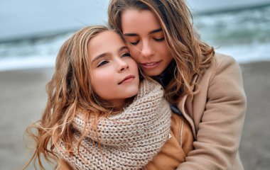 Güzel, genç bir anne ve güzel kızı kışın kumsalda..