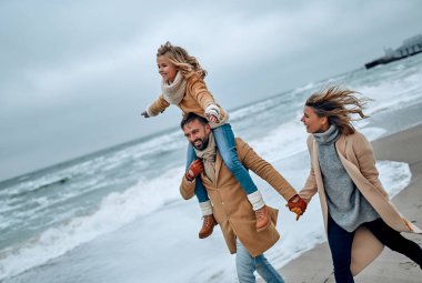 Genç evli bir çiftin ve kışın sahilde eğlenen tatlı kızlarının portresi..