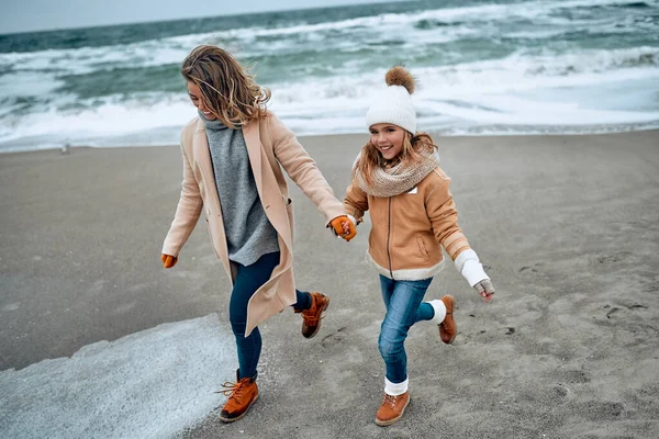 Paltolu güzel genç anne kışın kumsalda tatlı kızıyla eğleniyor..