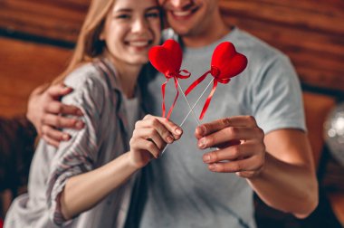 Sevgililer Günü 'nü kutlarken ellerinde kalp tutan, sarılan ve eğlenen genç bir çift..