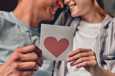 Yatak odasında sevgililer günü kartı tutan genç ve güzel bir çift görüntüsü. Sevgililer Günü 'nü kutluyoruz.