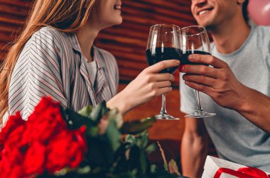 Yatak odasında şarap kadehleri, hediyeler ve kırmızı güllerle kesilmiş genç bir çift resmi. Sevgililer Günü. Yıldönümü. Doğum günü.