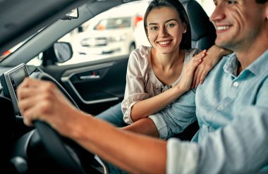 Araba galerisini ziyaret ediyorum. Güzel bir çift yeni arabalarında otururken gülümsüyor..