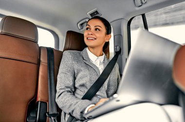 Arabada dizüstü bilgisayarı olan genç bir iş kadını. Lüks bir araçla işe giden kadın yönetici..