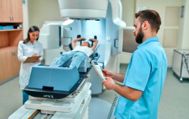 Genç bir kadın, modern bir kanser hastanesinde doktorların gözetiminde kanser için radyasyon tedavisi görüyor. Kanser terapisi, gelişmiş tıbbi hızlandırıcı..