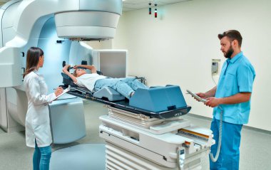 Genç bir kadın, modern bir kanser hastanesinde doktorların gözetiminde kanser için radyasyon tedavisi görüyor. Kanser terapisi, gelişmiş tıbbi hızlandırıcı..