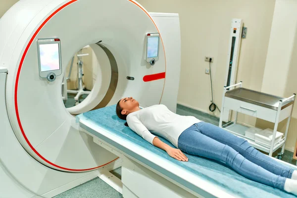 Tomografide veya MR 'da yatan bir hastanın portresi, yatak makinenin içinde hareket ediyor, vücudunu ve beynini tarıyor. Yüksek teknolojili ekipmanlarla dolu bir tıp laboratuvarında..