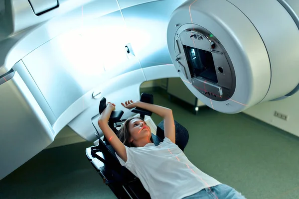 A young woman is undergoing radiation therapy for cancer in a modern cancer hospital. Cancer treatment, modern medical linear accelerator.