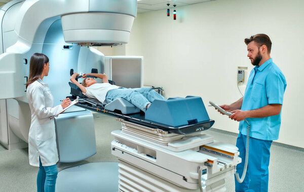 A young woman is undergoing radiation therapy for cancer under the supervision of doctors in a modern cancer hospital. Cancer therapy, advanced medical linear accelerator.