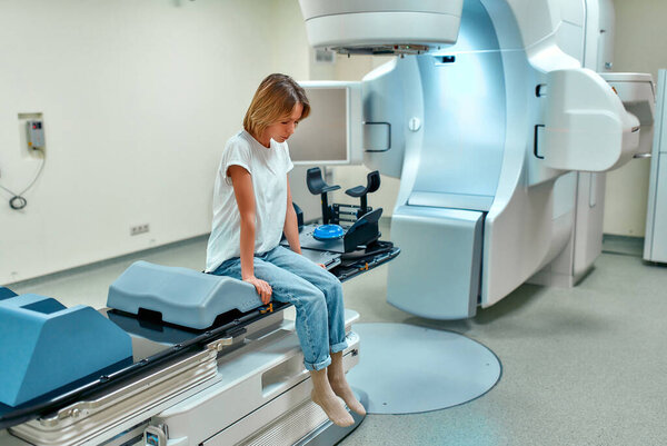 A young woman is undergoing radiation therapy for cancer in a modern cancer hospital. Cancer treatment, modern medical linear accelerator.