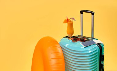 Çanta, kokteyl, biletler ve sarı arka planda izole edilmiş lastik yüzük. Eğlence, seyahat, turizm konsepti. Boş aksesuarlar.