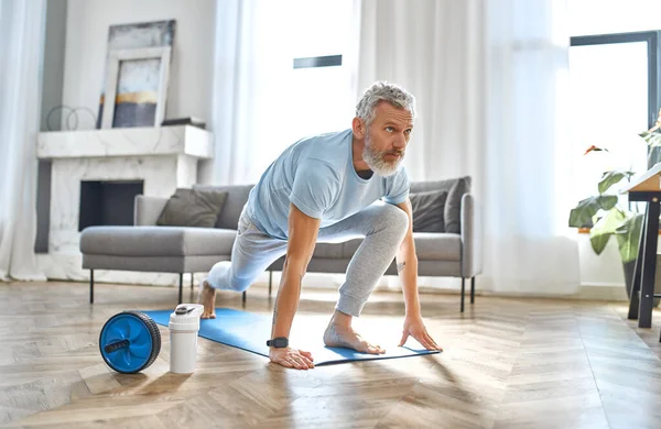 Spor, spor ve sağlıklı yaşam tarzı konsepti. Evde egzersiz yapan olgun bir adam. Karantina konseptiyle nasıl sağlıklı kalınır?.