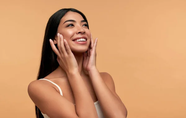 Beyaz bluzlu, temiz, parlak derili genç Asyalı kadın bej arka planda izole edilmiş. Yüz bakımı konsepti, spa, kozmetoloji, estetik cerrahi.
